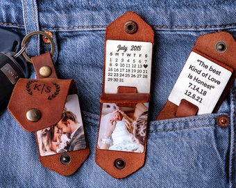 May include: Two leather photo holders with a key chain. The first holder has a photo of a couple and the initials "K/S" engraved on it. The second holder has a photo of a baby and a calendar for July 2018. The third holder has a silver plate with the text "The best Kind of Love Is Honest" and the dates "7.14.18" and "12.5.21".