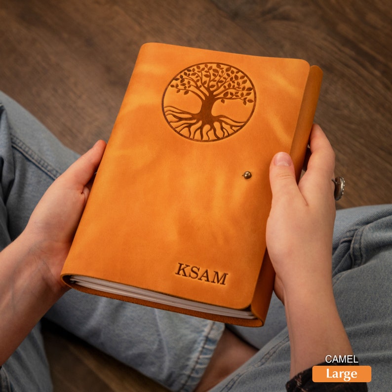 Pu&ograve; includere: Diario in pelle color cammello con un disegno ad albero della vita in rilievo sulla copertina. Il diario ha una chiusura a scatto e le iniziali KSAM sono incise sul davanti. Il diario &egrave; etichettato "Large".