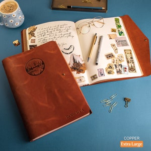 A4 leather sketchbook with removable paper pads, featuring a clasp, custom embossed mountains on top, and a name in the bottom right