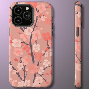 May include: A pink phone case with a floral design featuring pink and white cherry blossoms. The case has a black camera lens cutout.