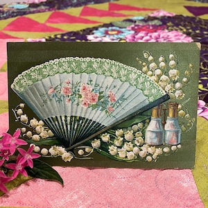 Cartão postal antigo em relevo - Leque de mão com renda verde suave e flores, fundo com acabamento em lírio do vale e cetim texturizado - Leque dobrável