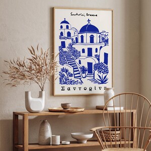 Puede incluir: Una ilustraci&oacute;n azul y blanca de una iglesia en Santorini, Grecia. El texto "Santorini, Greece" y "&Sigma;&alpha;&nu;&tau;&omicron;&rho;ί&nu;&eta;" est&aacute; impreso en el p&oacute;ster.