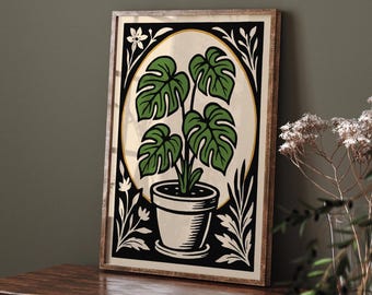 May include: A framed botanical print featuring a potted Monstera plant. The artwork has a cream-colored background with a black and gold border. The plant has large green leaves and is in a white pot. The frame is made of wood.