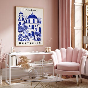 Puede incluir: Una impresi&oacute;n enmarcada en blanco con una ilustraci&oacute;n azul de un pueblo griego con el texto "Santorini, Grecia" y "&Sigma;&alpha;&nu;&tau;&omicron;&rho;ί&nu;&eta;" en la parte superior e inferior de la imagen.
