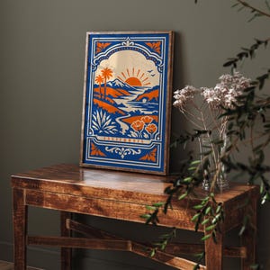 May include: A framed art print featuring a California landscape design. The artwork showcases a sunset over mountains, palm trees, and a river, with the word "CALIFORNIA" at the bottom. The color palette includes blue, orange, and beige.