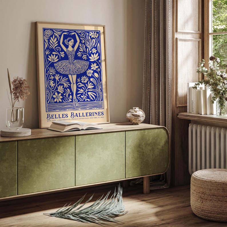 May include: A gold framed poster with a blue and white illustration of a ballerina dancing in a field of flowers. The text "BELLES BALLERINES" is at the bottom of the poster.