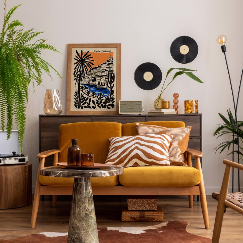 May include: A cozy living room scene with a mustard yellow sofa, a marble-topped coffee table, and a wooden cabinet. The room is decorated with a framed print, vinyl records, and decorative pillows. A fern and a floor lamp add to the ambiance.