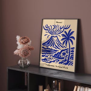 Puede incluir: Impresi&oacute;n art&iacute;stica enmarcada con una ilustraci&oacute;n azul de un volc&aacute;n, una palmera y una escena oce&aacute;nica sobre un fondo beige. El texto "Hawaii" est&aacute; en la parte superior y "Volcanoes National Park" en la inferior. La obra de arte se exhibe en una estanter&iacute;a gris oscuro.