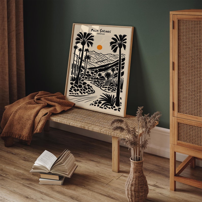 Pode incluir: Ilustra&ccedil;&atilde;o em preto e branco de palmeiras e uma paisagem des&eacute;rtica com o sol se pondo. A impress&atilde;o &eacute; emoldurada e pendurada em uma parede acima de um banco de madeira. O texto "Palm Springs, Calif&oacute;rnia" est&aacute; impresso na impress&atilde;o.