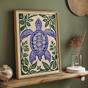 May include: Framed art print featuring a blue turtle design with intricate details, surrounded by green foliage on a cream background. The artwork is set within a natural wood frame, creating a coastal or nature-inspired aesthetic.