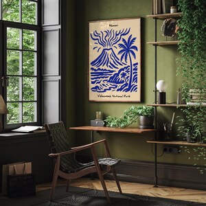 Puede incluir: Un p&oacute;ster enmarcado con un dise&ntilde;o azul y beige que representa un volc&aacute;n, una palmera y una escena oce&aacute;nica. El texto "Hawaii" y "Volcanoes National Park" son visibles. El p&oacute;ster cuelga de una pared verde en una habitaci&oacute;n con un escritorio y una silla de madera.