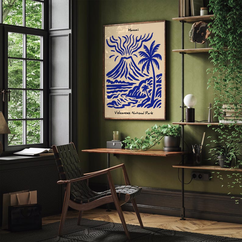 Puede incluir: Un p&oacute;ster enmarcado con un dise&ntilde;o azul y beige que representa un volc&aacute;n, una palmera y una escena oce&aacute;nica. El texto "Hawaii" y "Volcanoes National Park" son visibles. El p&oacute;ster cuelga de una pared verde en una habitaci&oacute;n con un escritorio y una silla de madera.