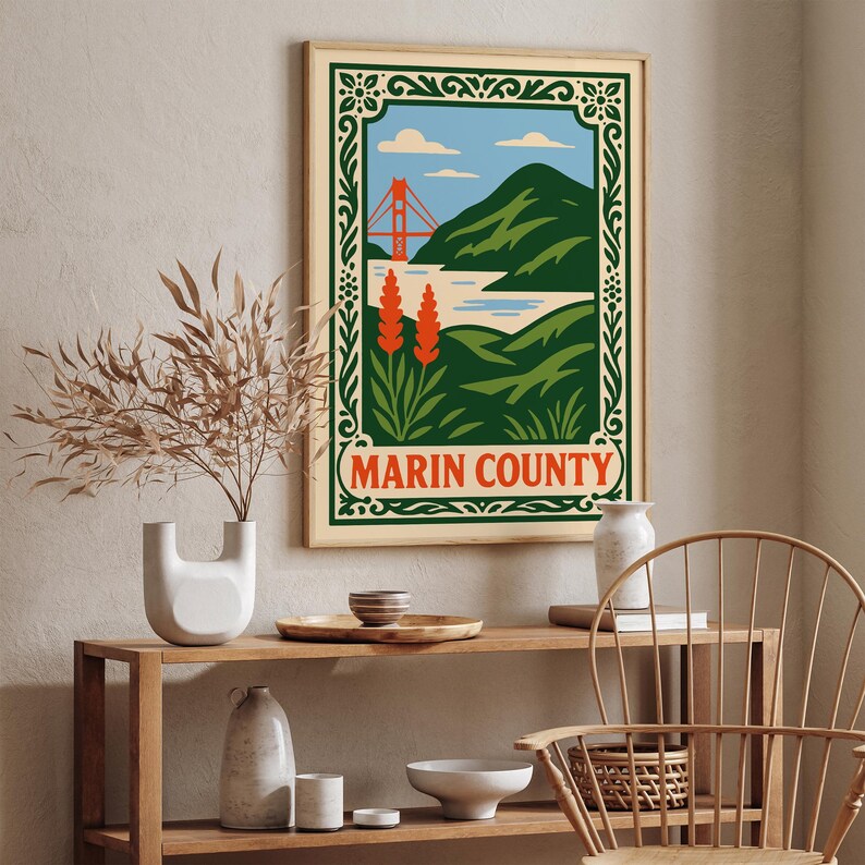 May include: A framed poster of Marin County, California, with a vintage travel-style design. It depicts the Golden Gate Bridge, green hills, and blue sky. The poster has a green border and the words "Marin County" in a red and white oval.