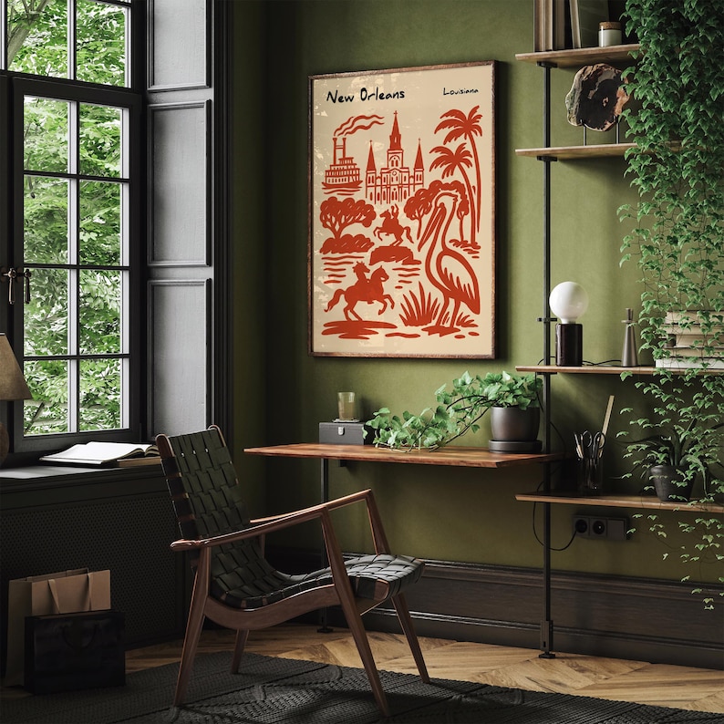 Op de afbeelding: Een ingelijste poster met een vintage ontwerp met de tekst "New Orleans" en "Louisiana" in een rood-beige kleurenschema. Het kunstwerk toont iconische stadselementen, waaronder gebouwen, bomen en een pelikaan. De poster wordt weergegeven in een kamer met een houten bureau en stoel.