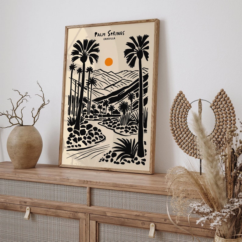 Pode incluir: Uma ilustra&ccedil;&atilde;o em preto e branco de palmeiras e um rio sinuoso em uma paisagem des&eacute;rtica. O texto "Palm Springs, CAHUILLA" est&aacute; no topo da imagem.