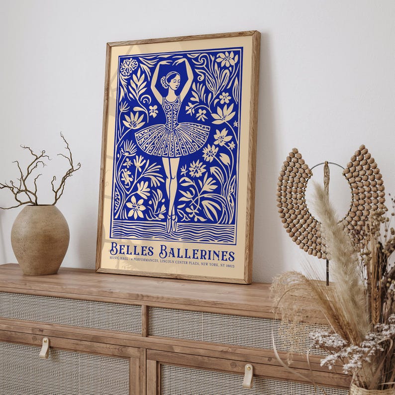 May include: A gold framed poster with a blue illustration of a ballerina dancing in a field of flowers. The text "BELLES BALLERINES" is at the bottom of the poster.