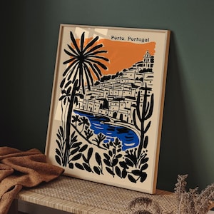 May include: Framed art print featuring a stylized illustration of Porto, Portugal. The artwork depicts a coastal town with white buildings, a blue river, and palm trees, set against an orange and beige background. The words "Porto, Portugal" are printed at the top.