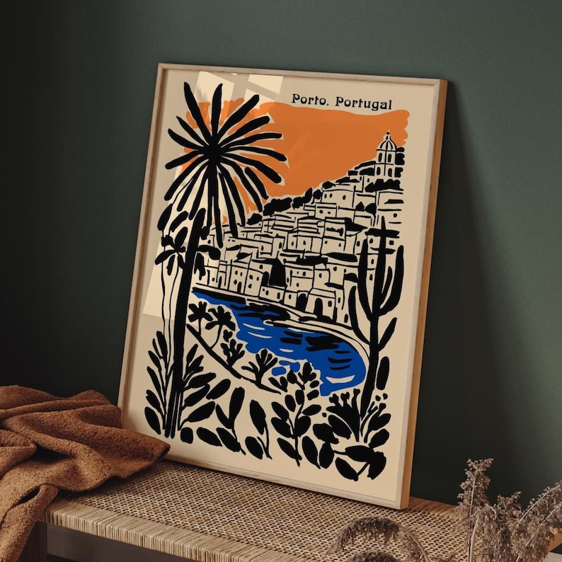 May include: Framed art print featuring a stylized illustration of Porto, Portugal. The artwork depicts a coastal town with white buildings, a blue river, and palm trees, set against an orange and beige background. The words "Porto, Portugal" are printed at the top.