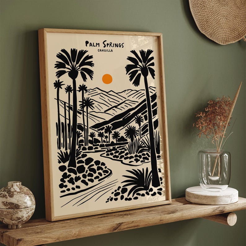 Pode incluir: Ilustra&ccedil;&atilde;o em preto e branco de palmeiras e montanhas com um sol poente ao fundo. O texto "Palm Springs, CAHUILLA" est&aacute; no topo da imagem.