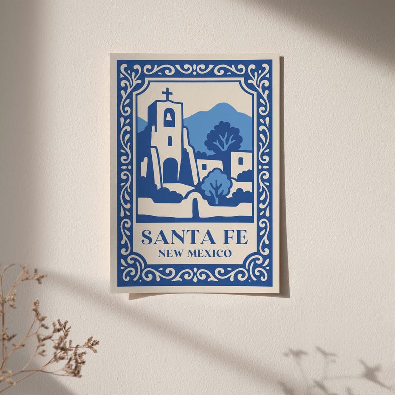 May include: A blue and white art print of Santa Fe, New Mexico. The print depicts a church and mountain scene within a decorative border. The words "SANTA FE NEW MEXICO" are printed at the bottom of the image.