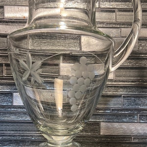 A beautiful clear pitcher with grapes etched on it