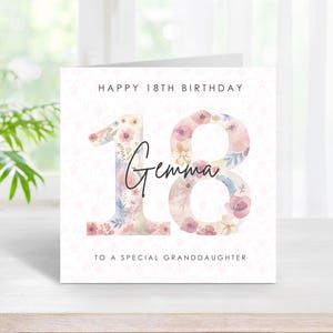 Puede incluir: Una tarjeta de felicitación cuadrada con el texto HAPPY 18TH BIRTHDAY en la parte superior y TO A SPECIAL GRANDDAUGHTER en la parte inferior. El número 18 aparece en el centro con un estampado floral en tonos rosa, azul y crema, con el nombre Gemma.