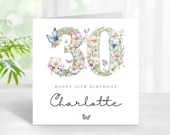 Puede incluir: Tarjeta de cumpleaños blanca con el número "30" formado por flores y mariposas. La tarjeta dice "Happy 30th Birthday" y "Charlotte" en escritura elegante. Una pequeña mariposa está en la parte inferior.