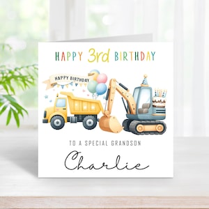 May include: A birthday card featuring a yellow dump truck and a blue excavator illustration. The card says "Happy 3rd Birthday" and "To a special grandson Charlie."