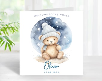 May include: A greeting card with a watercolor illustration of a teddy bear wearing a hat and scarf. The card reads "Welcome to the World" above the bear and has the name "Oliver" and the date "15.08.2025" below the bear.