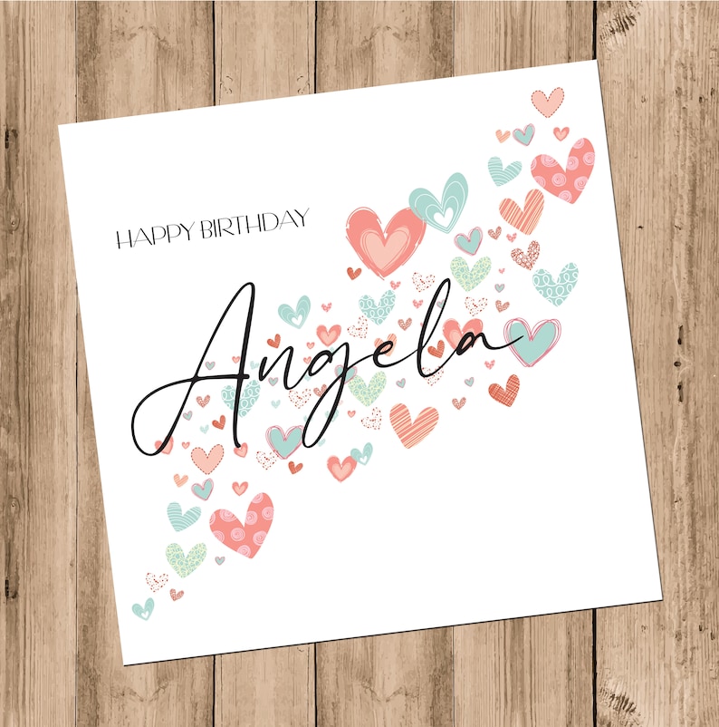 May include: A white card with the text "Happy Birthday Angela" in black script. The card is decorated with a scattering of pink, red, and blue hearts.