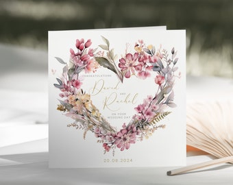 May include: A white wedding card with a watercolor floral heart design. The text reads "Congratulations David and Rachel on your wedding day 20.08.2024".