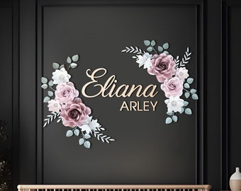 May include: A nursery room with a wooden crib and a wicker basket. The wall is black and has a floral paper flower arrangement with the name "Eliana Arley" written in gold lettering.