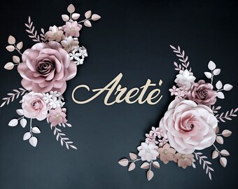 May include: A pink and white paper flower arrangement with the name "Areté" written in cursive on a black background.