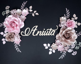 May include: A decorative floral arrangement featuring the name "Aniuta" in cursive script. The design includes large paper roses in shades of pink and taupe, with smaller accent flowers and leaves, all set against a dark background.