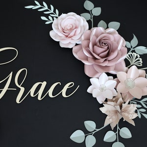 May include: A paper flower arrangement with the name "Grace" in gold script lettering. The flowers are in shades of pink and white, with green leaves.