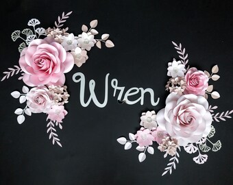 May include: A pink and white paper flower arrangement with the name "Wren" written in cursive on a black background.