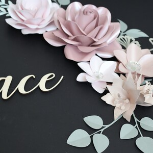 May include: A paper flower arrangement with pink and white flowers and green leaves. The word "Grace" is written in gold lettering on a black background.
