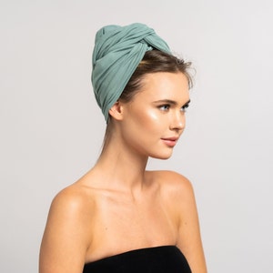 Könnte beinhalten: Eine Frau mit langen braunen Haaren trägt einen hellblauen Turban. Der Turban ist aus weichem, dehnbarem Stoff und oben auf dem Kopf gebunden.