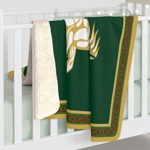 May include: A green fleece throw blanket with a gold Celtic knot border and a white and gold stylized animal design in the center.