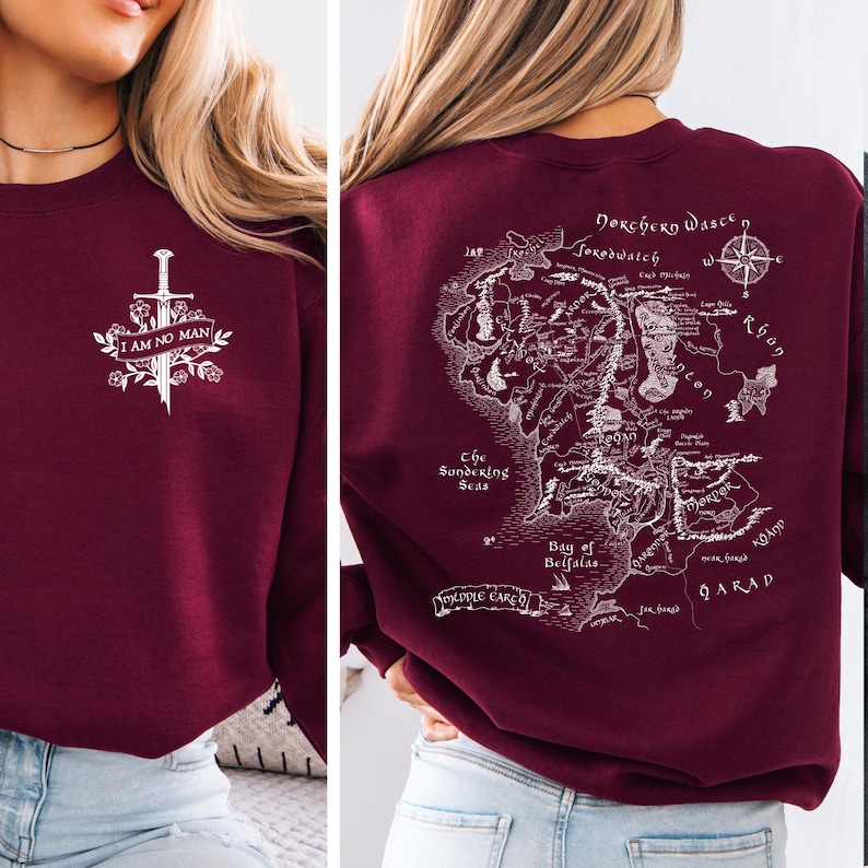 May include: Burgundy sweatshirt with a white graphic on the front that says "I AM NO MAN" with a sword and floral design. The back features a detailed map with text including "Dorchery Wasce" and "Bay of Belfalas".