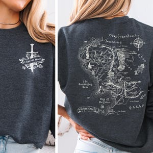 May include: Dark gray sweatshirt with a white sword and floral design, and the text "I AM NO MAN" on the front. The back features a detailed map with text, including "Middle Earth" and "Bay of Belfalas".