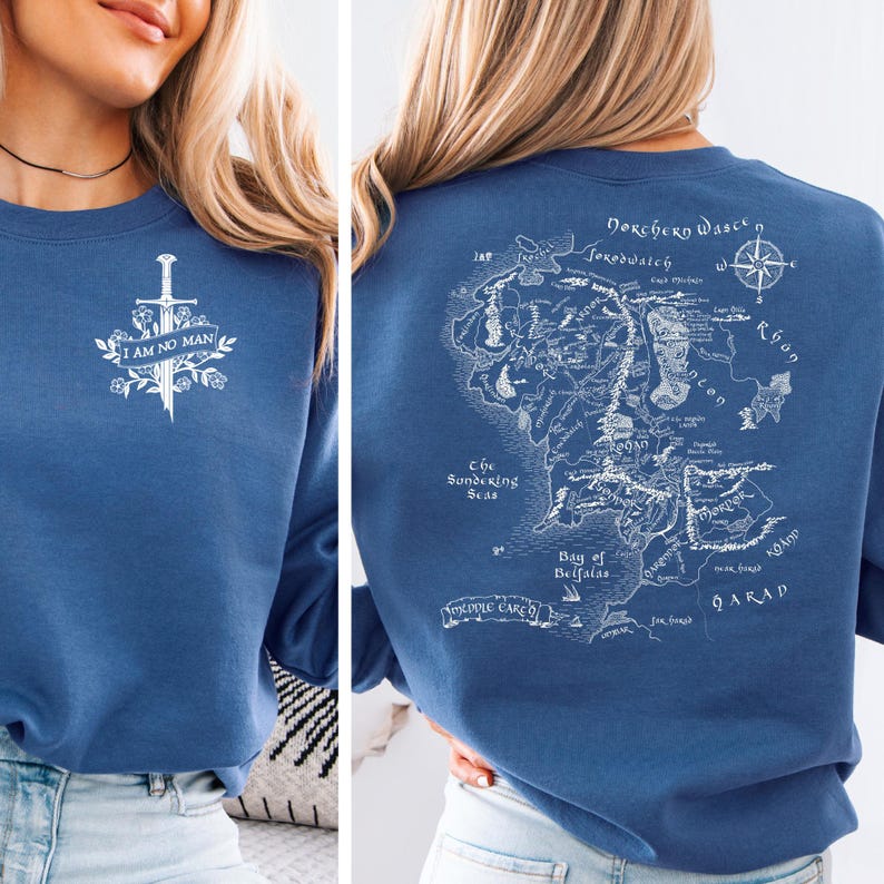 May include: Blue sweatshirt with a white graphic on the front featuring a sword, floral elements, and the text "I AM NO MAN." The back displays a detailed map with text and a compass rose.