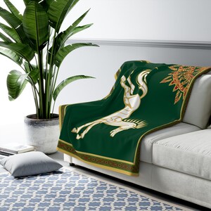 May include: A green fleece throw blanket with a white horse design and gold and red trim. The horse is stylized and has a Celtic knot design.
