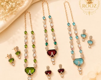 Conjunto de joyas llamativas en oro rosa, verde esmeralda y azul marino: collar y pendientes.