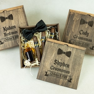 May include: Three wooden gift boxes with personalized engravings for a best man and groomsmen. Each box includes a bow tie, miniature liquor bottle, and cigars.