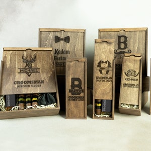 May include: Wooden gift boxes with engraved designs and names. The boxes are for groomsmen and the best man. Some boxes include cigars and a bow tie.