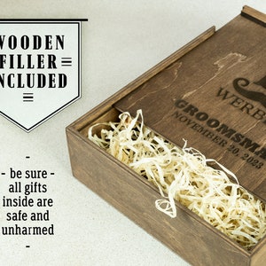 May include: A wooden box with a lid, filled with wood shavings. The lid is engraved with the text "GROOMSMAN" and "NOVEMBER 20, 2023" along with the name "WERBER" and the letter "B".