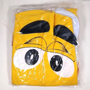 May include: A yellow costume with a large cartoon eye design, packaged in clear plastic. The costume features black eyebrows and large white and black eyes. The costume is folded and appears to be new.