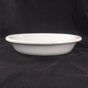 以下が含まれることがあります： わずかに盛り上がった縁のある白い楕円形のセラミック製のベーキングディッシュです。