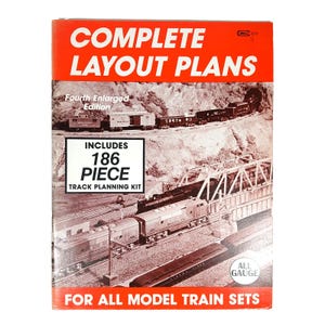 Op de afbeelding: Een boek getiteld COMPLETE LAYOUT PLANS Fourth Enlarged Edition met een zwart-witfoto van modeltreinen op rails en een brug. De omslag bevat de tekst INCLUDES 186 PIECE TRACK PLANNING KIT en FOR ALL MODEL TRAIN SETS.